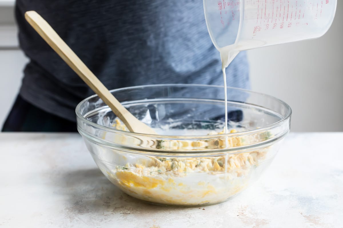 Hush puppy batter being made in a clear bowl.
