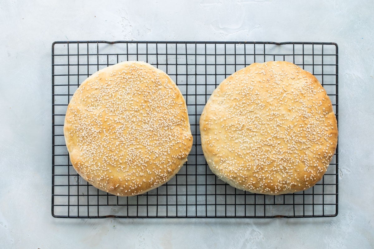 Baked muffaletta bread on a cooling rack.