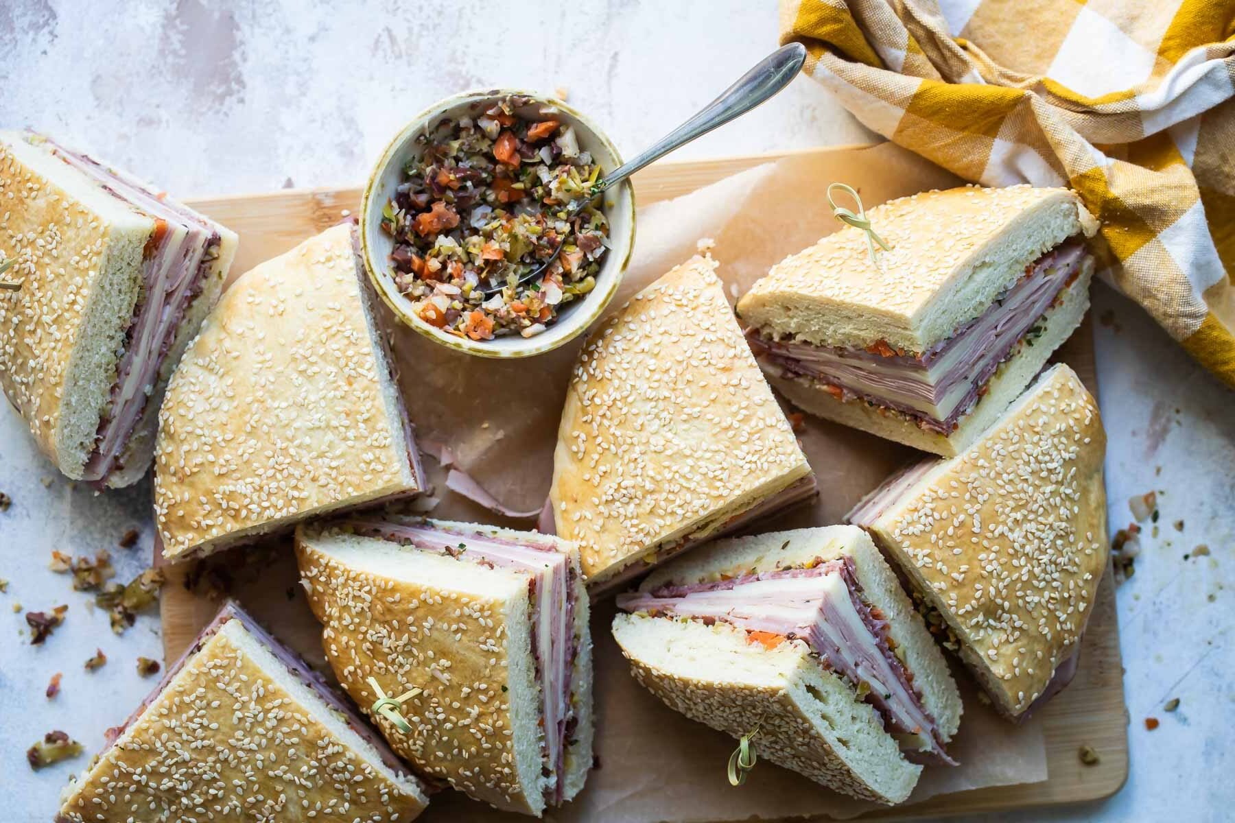 Muffaletta sandwich quarters on a wooden cutting board.