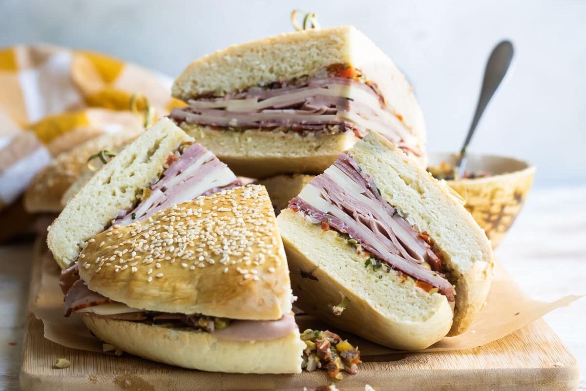 Muffaletta sandwich quarters on a wooden cutting board.