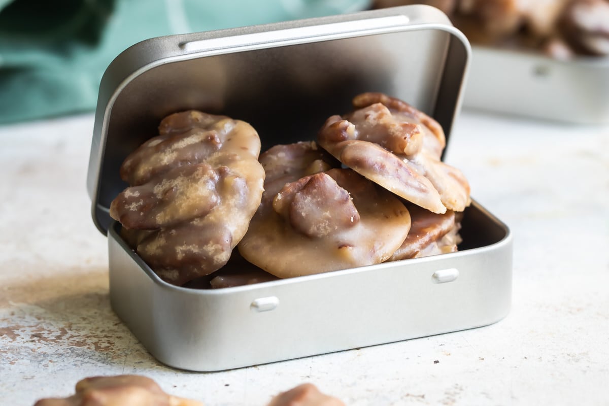 Pecan pralines in a small silver tin.