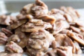 A stack of pecan pralines on a baking sheet.