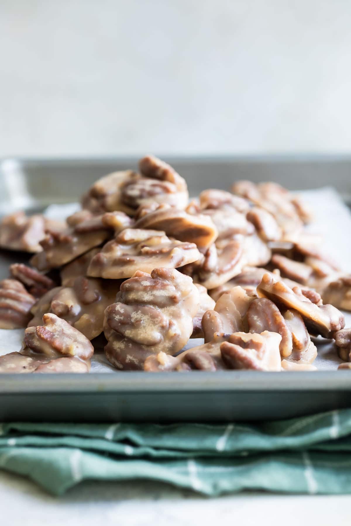 A stack of pecan pralines on a parchment paper lined baking sheet.