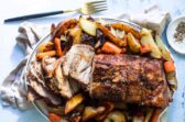 Pork roast on a plate with vegetables.