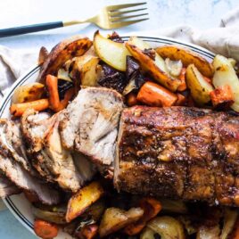 Pork roast on a plate with vegetables.