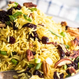 A plate of rice stuffing with a spoon resting in it.