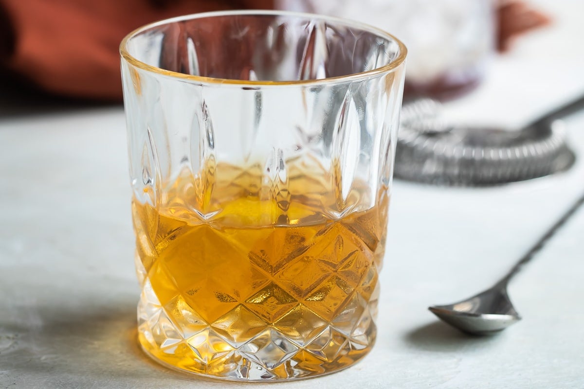 A Sazerac in a clear glass on a counter.
