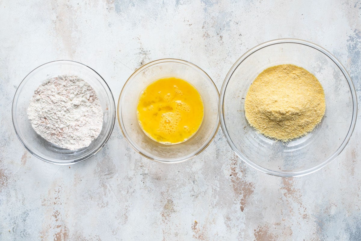 Three bowls with flour mixture, egg and cornmeal.