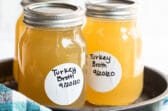 Three mason jars with turkey broth in them on a tray.