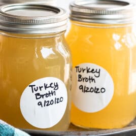 Three mason jars with turkey broth in them on a tray.