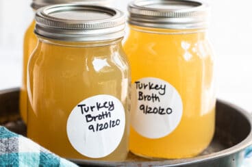 Three mason jars with turkey broth in them on a tray.
