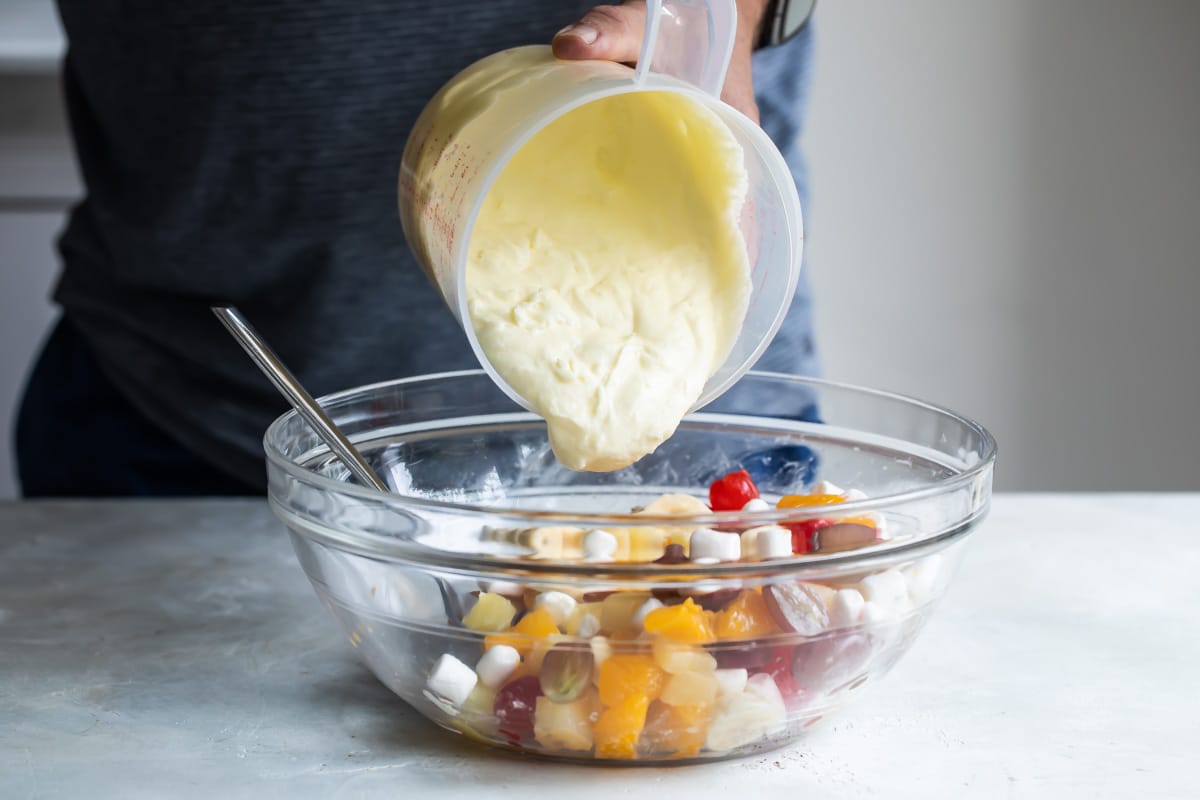 White pudding cream mixture being poured over fruit.