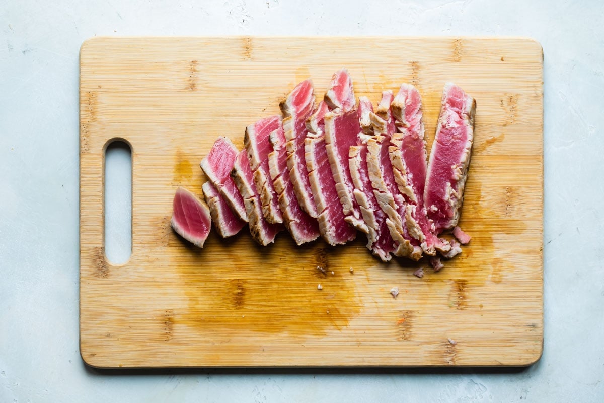 Ahi tuna slices on a wooden cutting board.