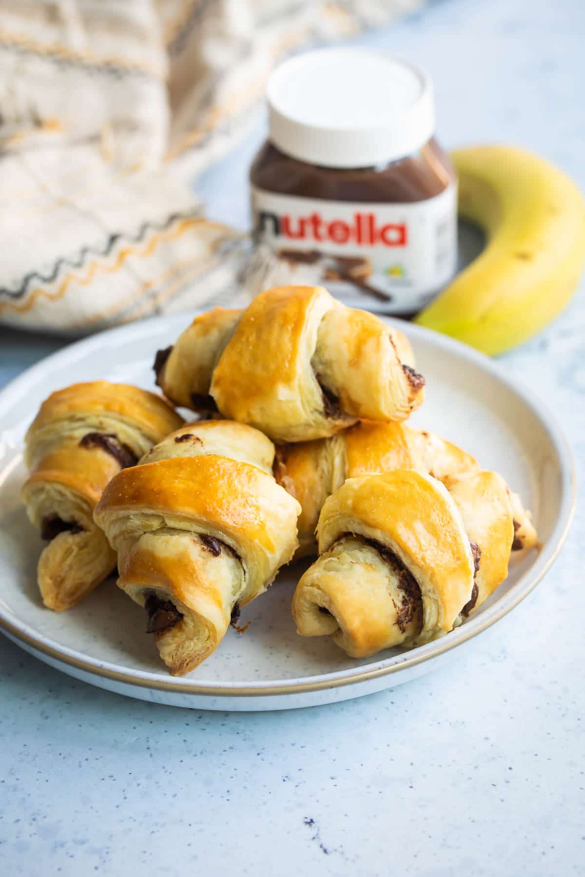 Baked banana nutella croissants on a white plate.