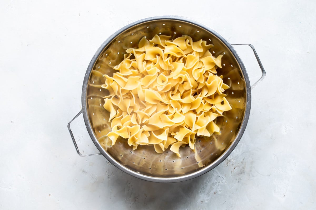Cooked egg noodles in a colander.
