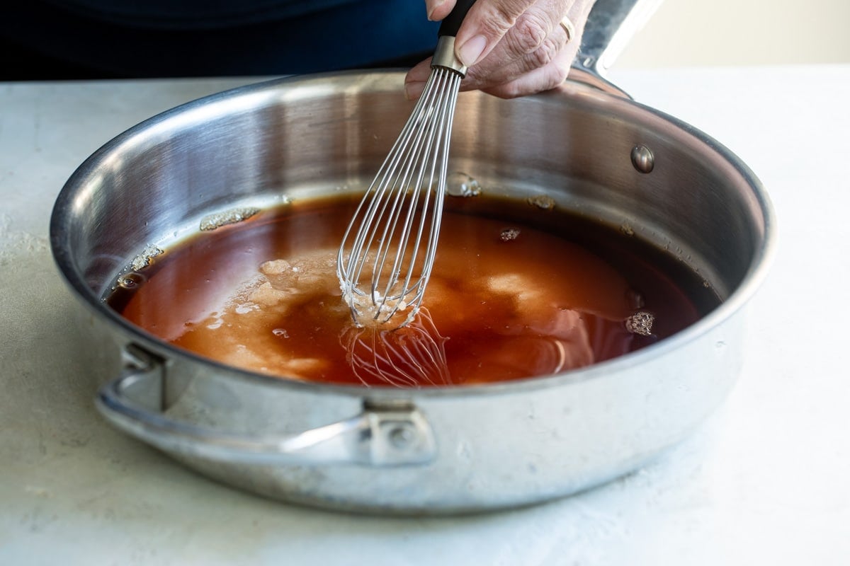 Brandy mixture in a silver skillet being whisked.