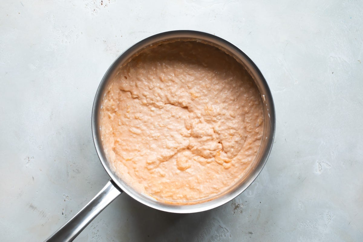 Cauliflower buffalo dip in a silver saucepan.