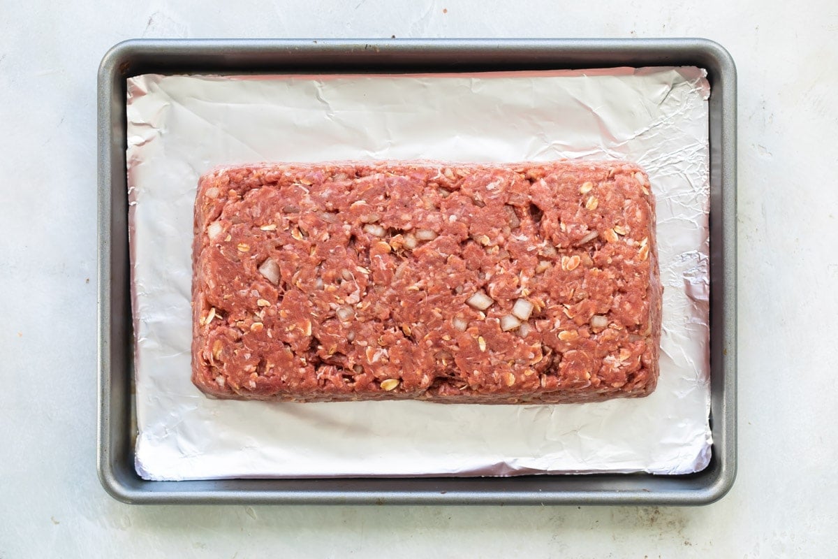 Cheesy meatloaf on a baking sheet before being baked.