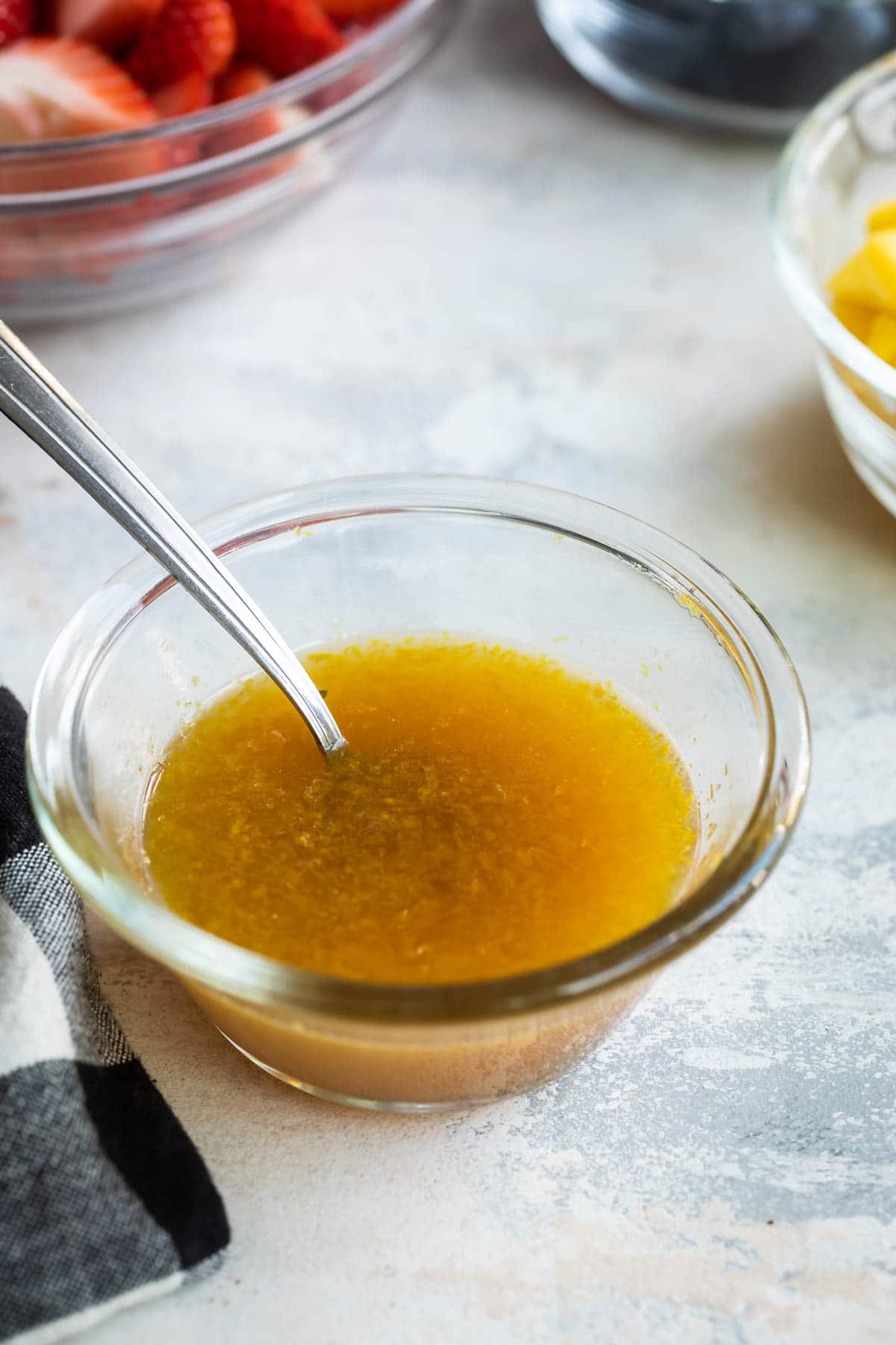 A small clear bowl of fruit salad dressing.
