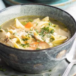 A gray bowl filled with leftover turkey noodle soup.