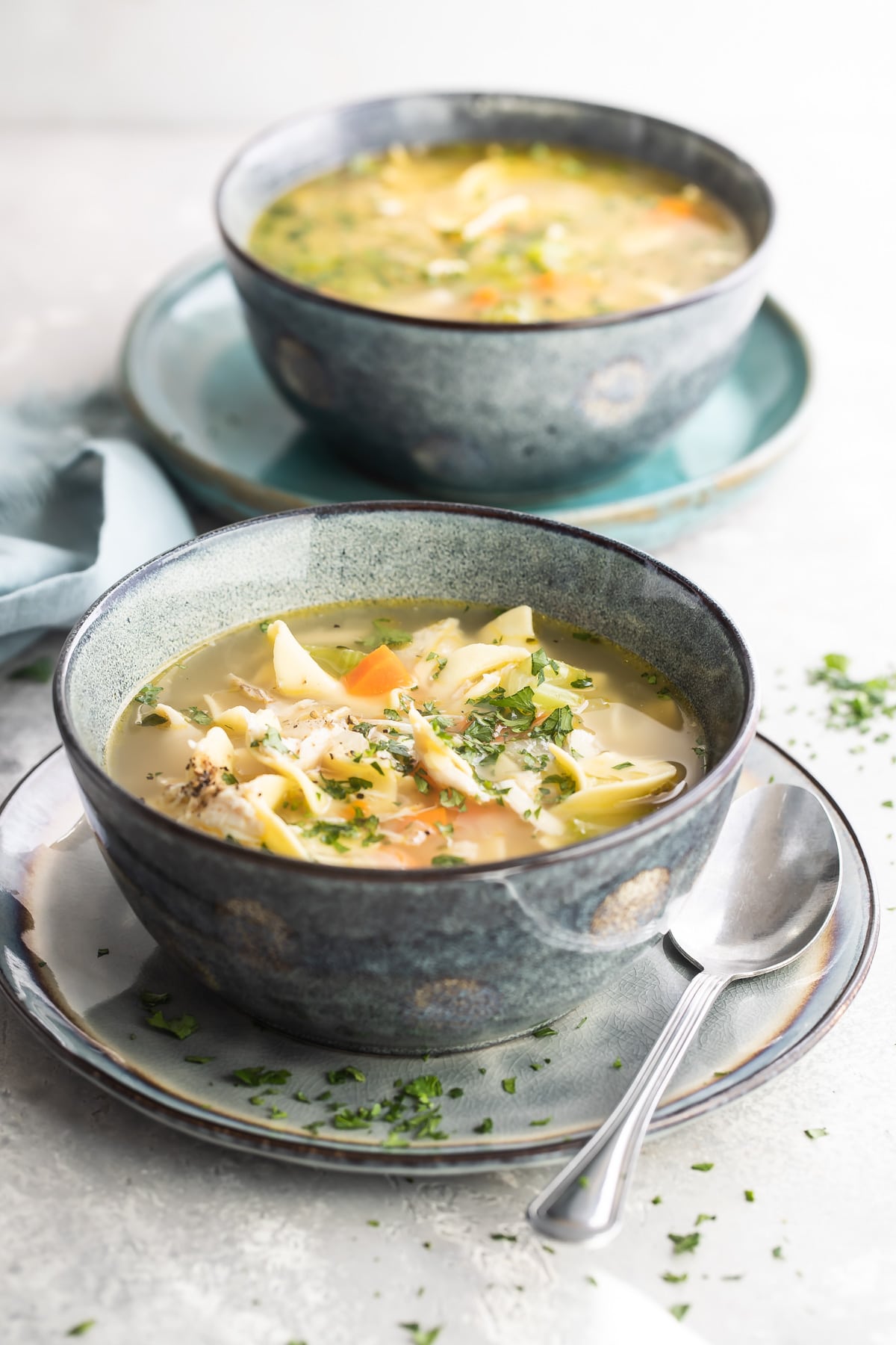 Two gray bowls filled with leftover turkey noodle soup.