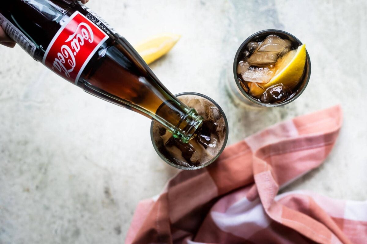 Coke being poured into a glass to make a lemon spezi.