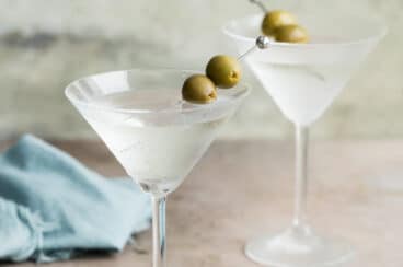 Two dry martinis garnished with green olives.