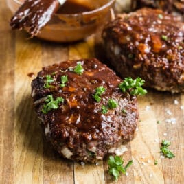Mini meatloaves with balsamic glaze on a wooden cutting board.