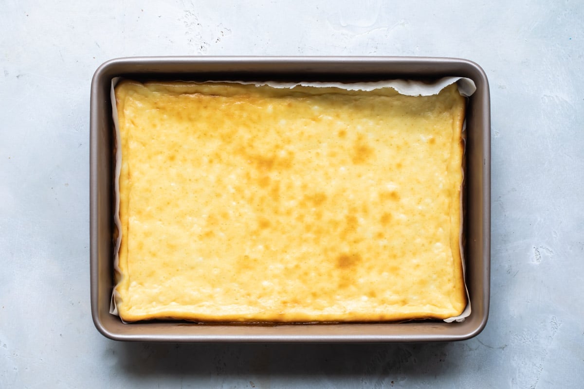 Sugar cookie cheesecake bars in a pan before being sliced.