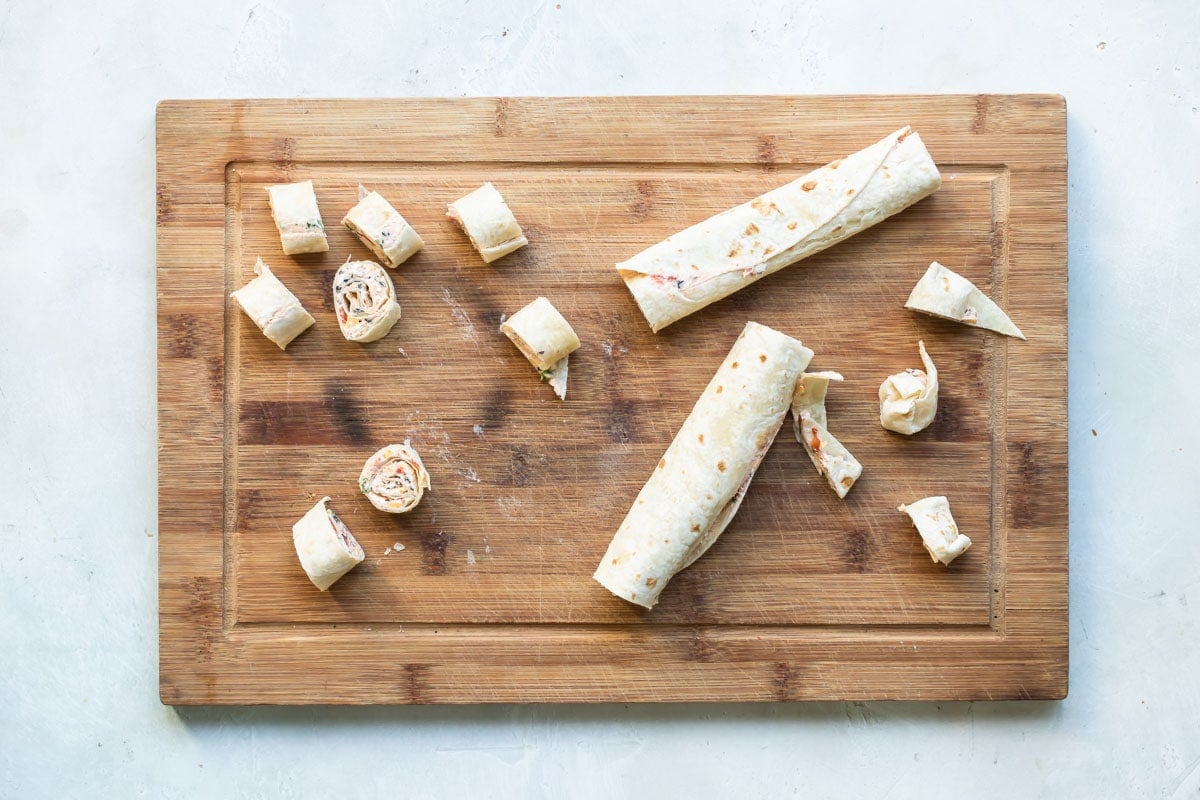Taco tortilla roll ups on a wooden cutting board.