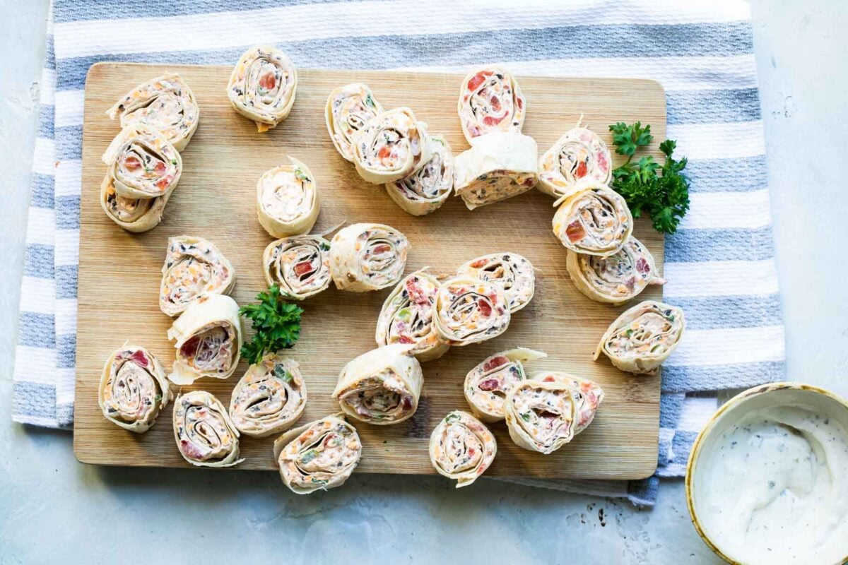 Taco tortilla roll ups on a wooden cutting board.