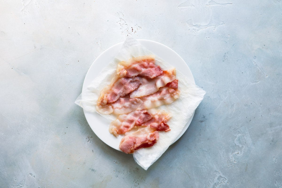 Bacon cooked limp on a paper towel lined plate.
