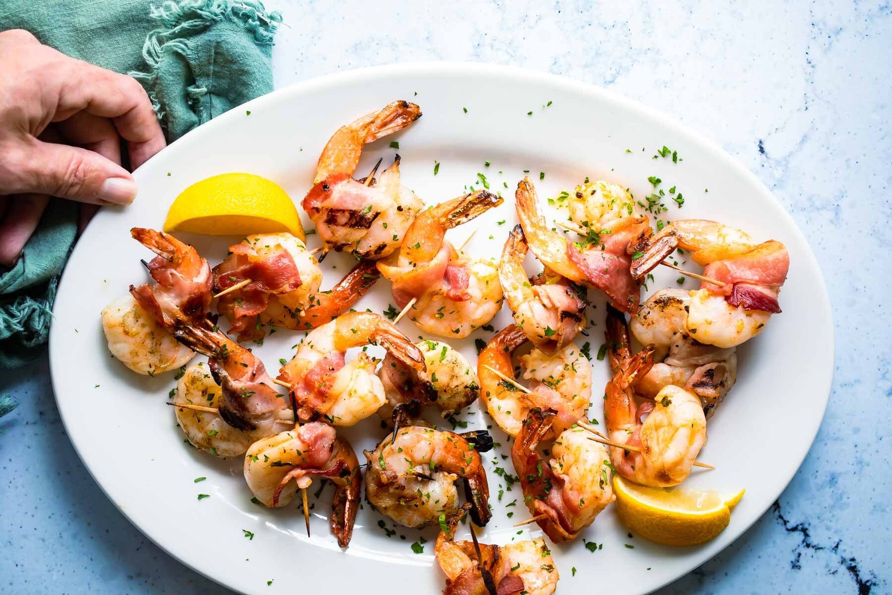 Bacon wrapped shrimp on a white serving platter.