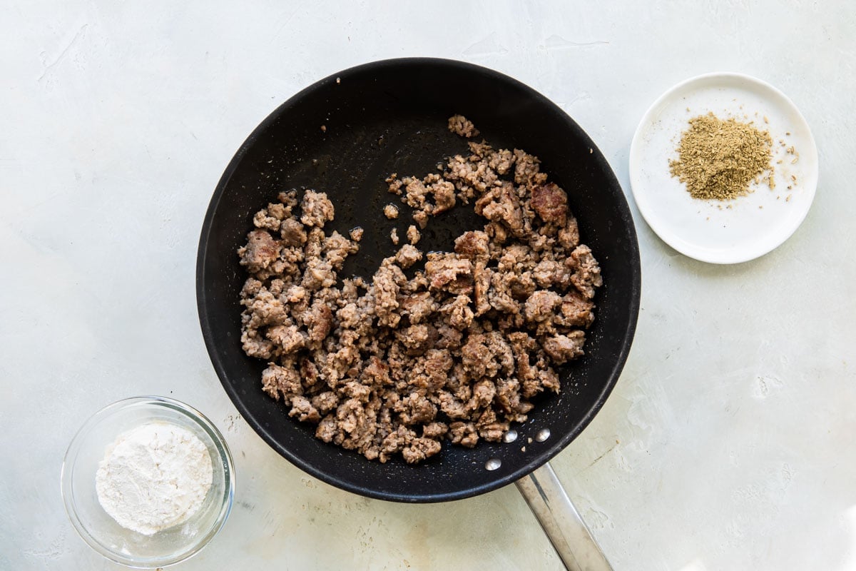 Ground sausage being cooked in a black skillet.