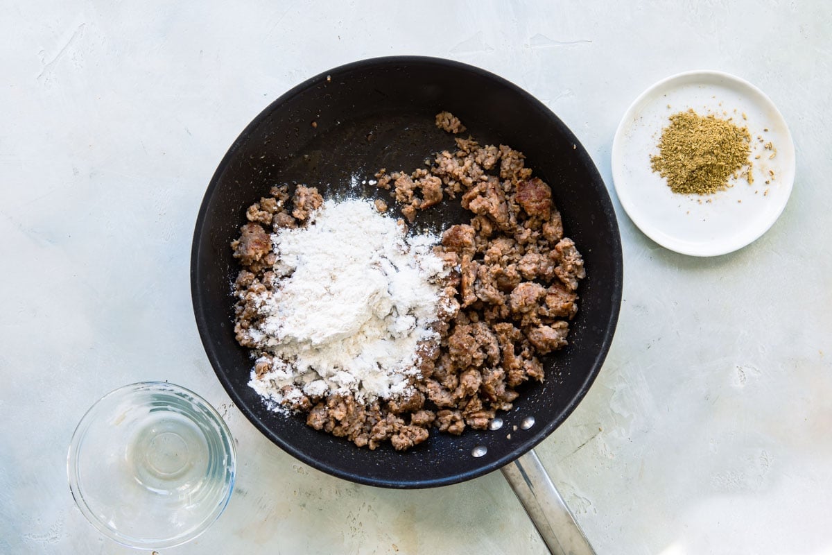 Sausage gravy being cooked in a black skillet.