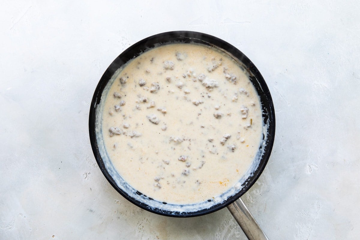 Sausage gravy being cooked in a black skillet.