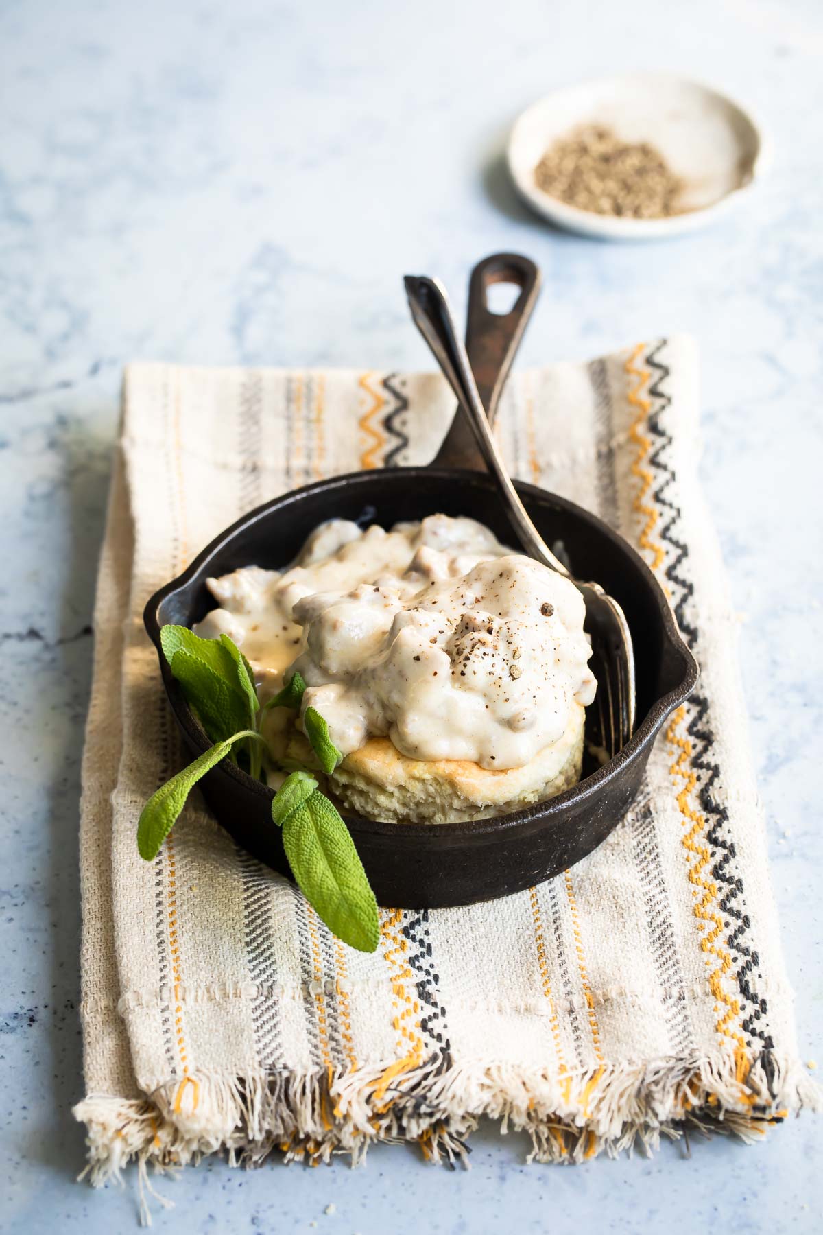 A skillet with biscuits and gravy in it.
