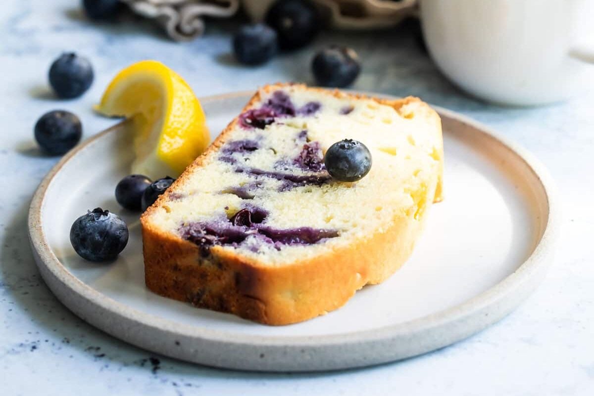 A slice of blueberry lemon yogurt cake on a gray plate.