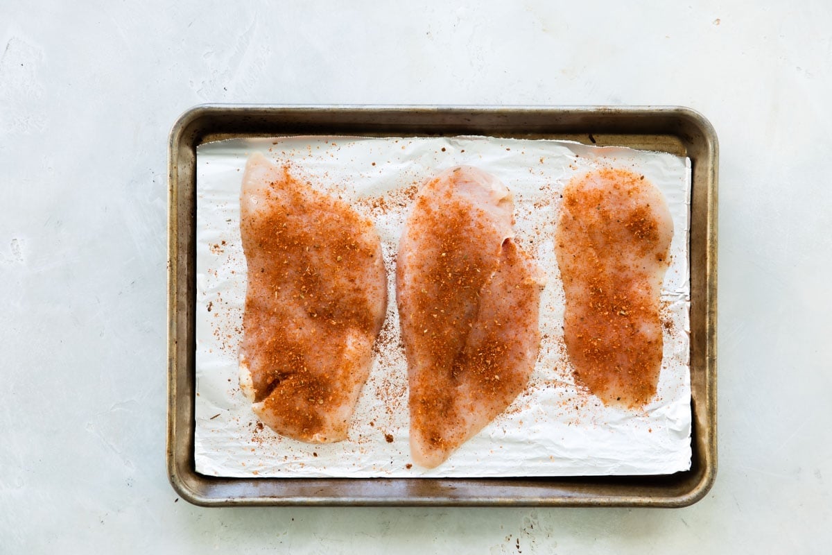 Raw chicken with cajun seasoning on top.