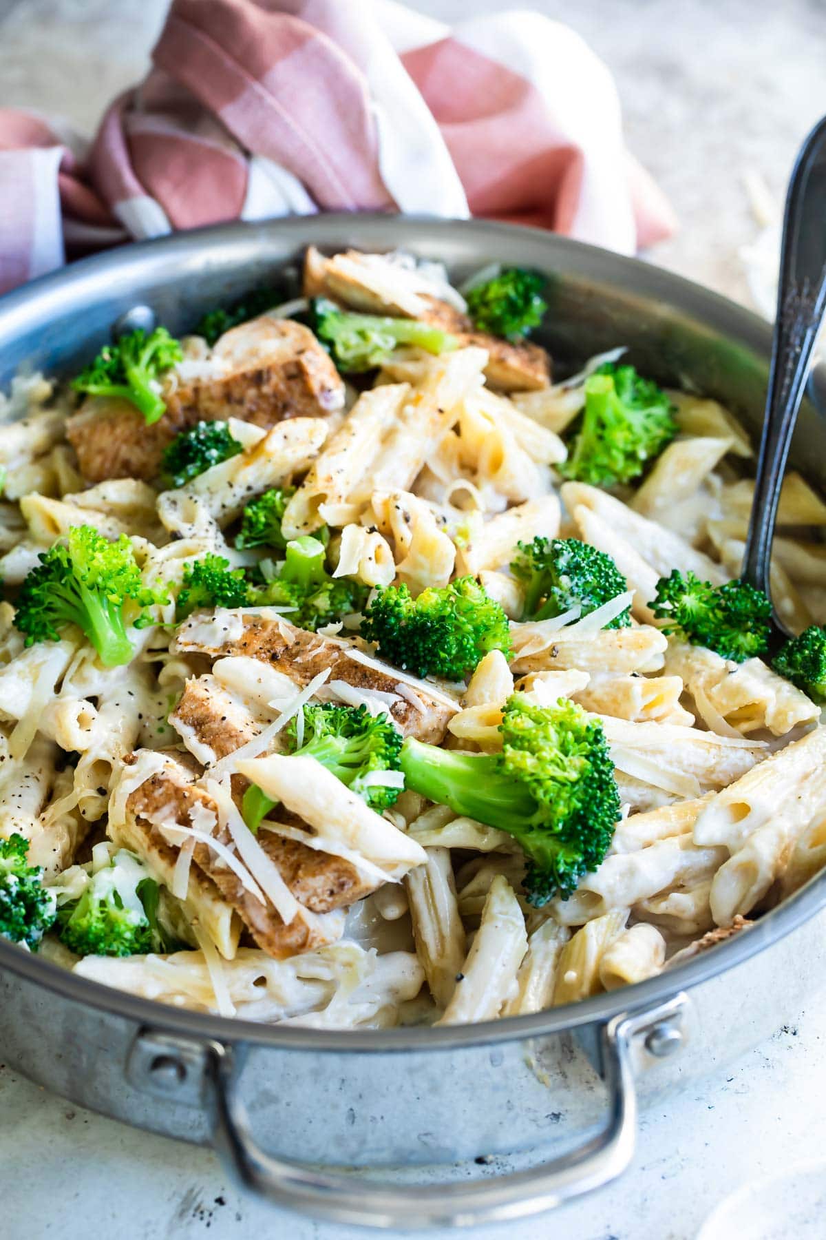 Cajun chicken alfredo with broccoli in a silver skillet.
