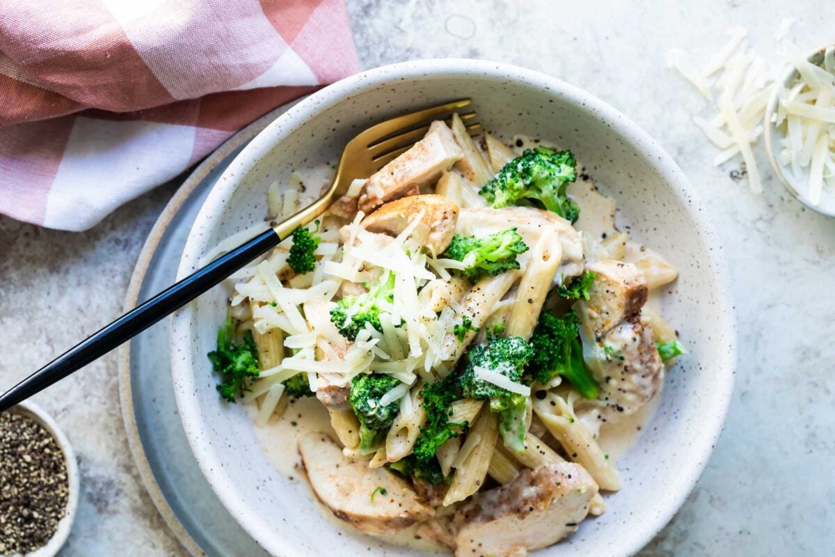 Cajun chicken alfredo with broccoli in a gray speckled bowl.