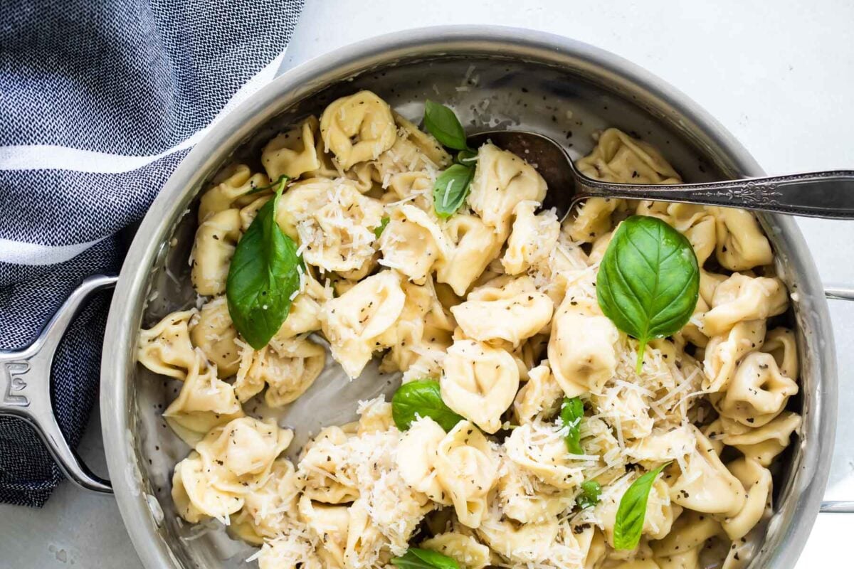 Cheese tortellini cooking in garlic butter sauce.