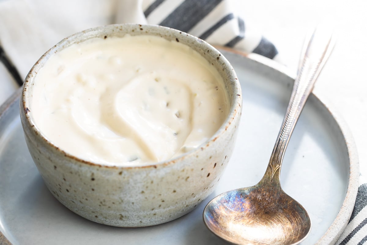 A bowl of remoulade sauce with a spoon next to it.