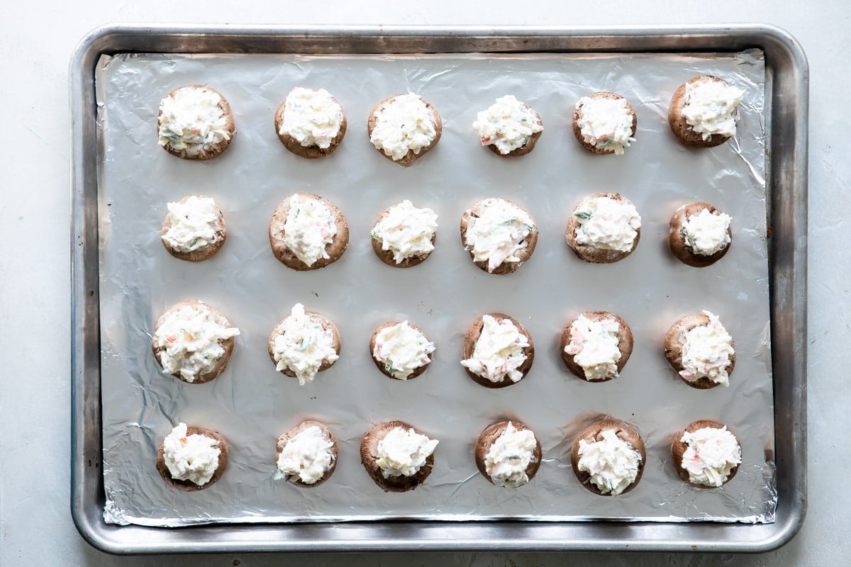 Crab stuffed mushrooms on a baking sheet before being baked.
