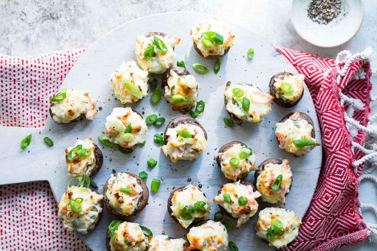Crab stuffed mushrooms on a wooden serving platter.