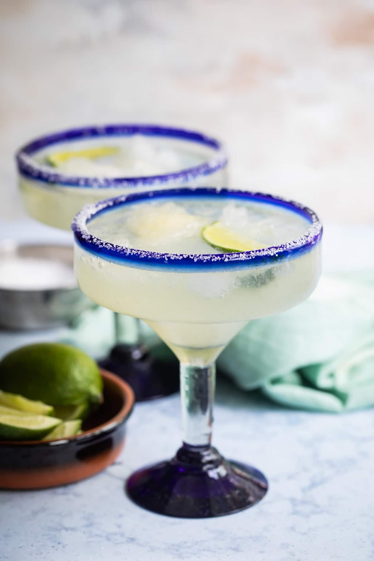 Two margaritas in blue-rimmed hand-blown Mexican margarita glasses.