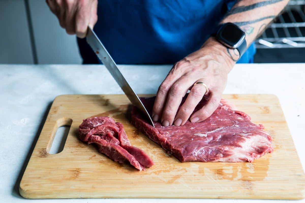 Cutting steak into strips against the grain of the meat.