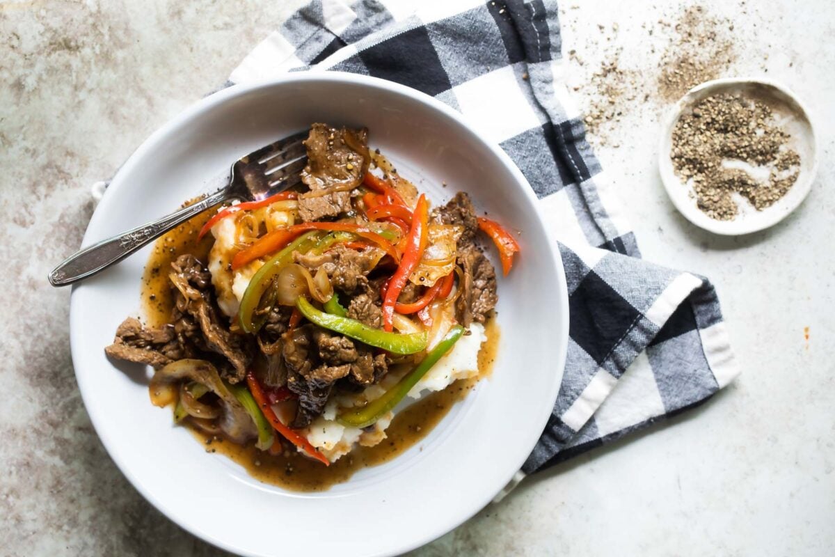 A bowl of Midwest Pepper Steak over mashed potatoes.