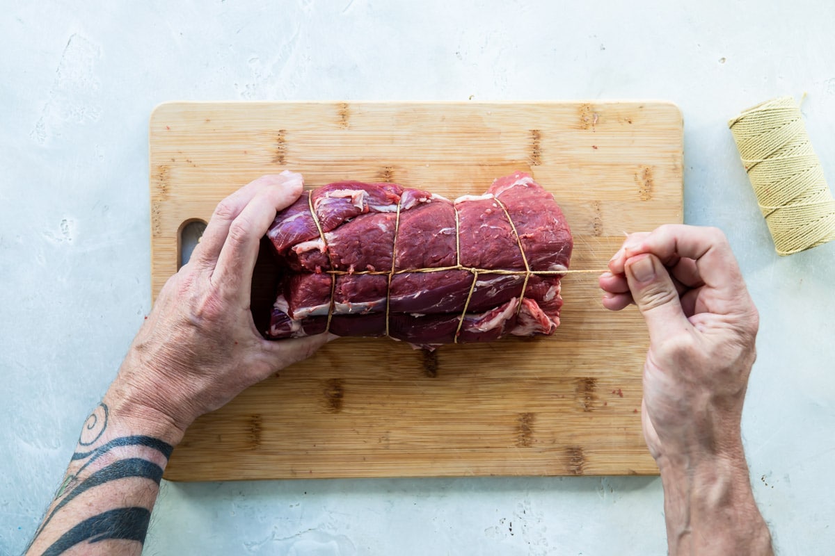 Tying a beef tenderloin with twine.