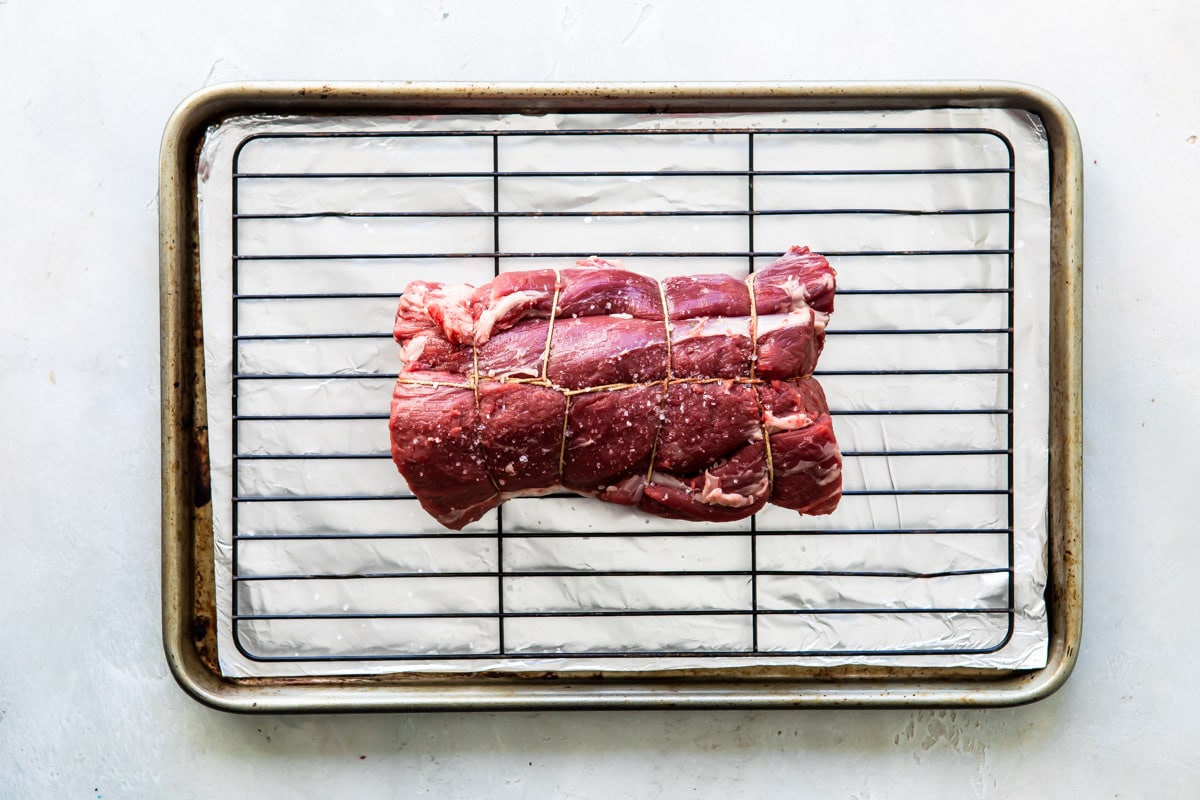 A tied beef tenderloin on a rack.